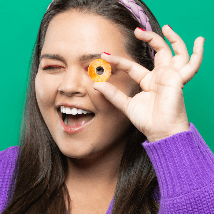 Woman with peach ring candy over eye smiling