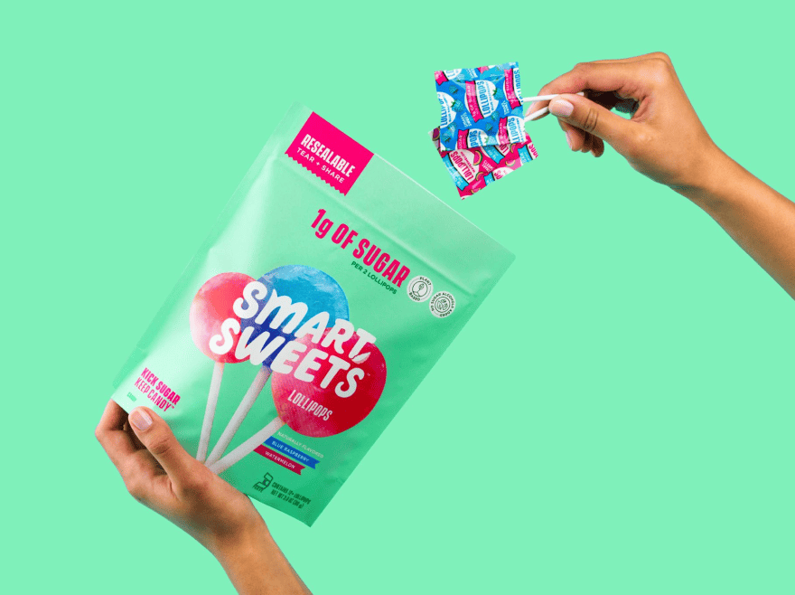 Holding 2 lollipops above lollipops pouch