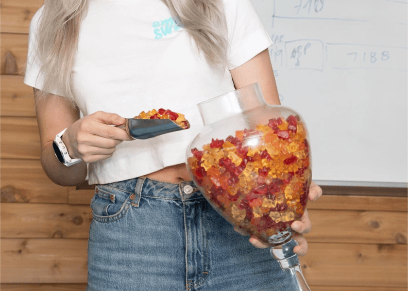 Scooping fruity gummy bears out of a jar