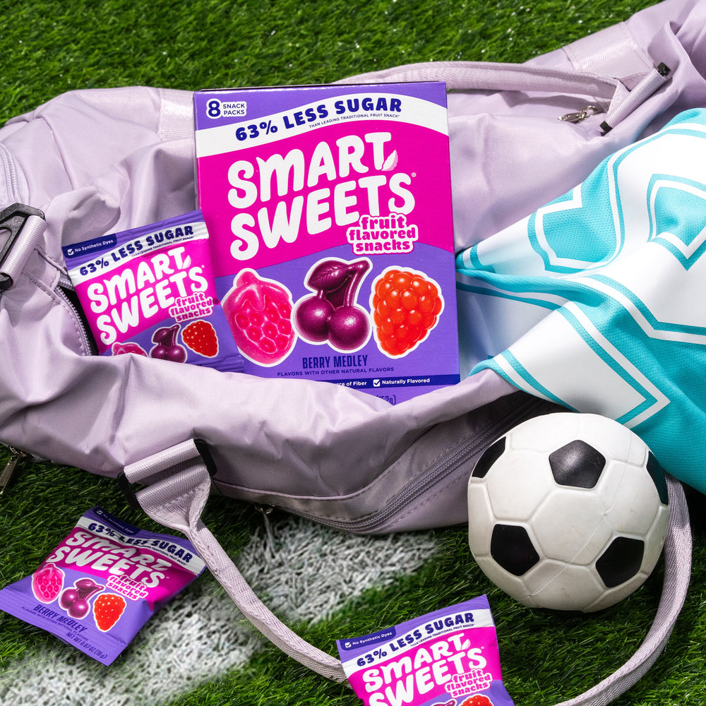 Smart Sweets fruit snacks packaging on a sports bag with a soccer ball on grass