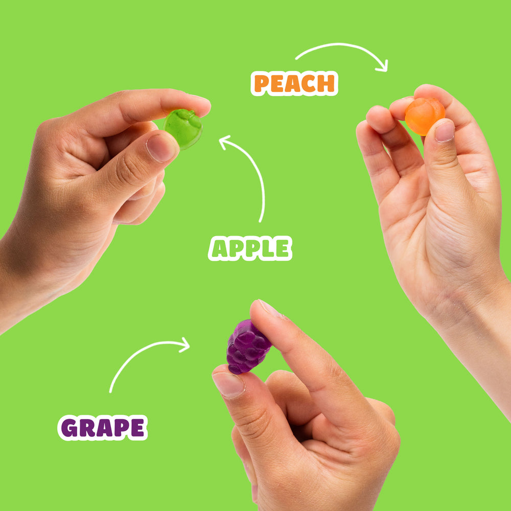 Hands holding fruit gummies. Text: PEACH, APPLE, GRAPE.