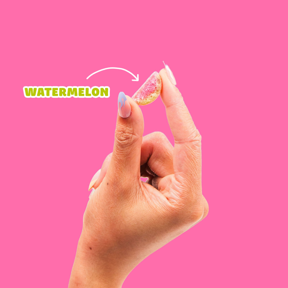 A sour watermelon gummy candy slice against a bright pink background. Text reads "WATERMELON" with an arrow pointing to the candy.