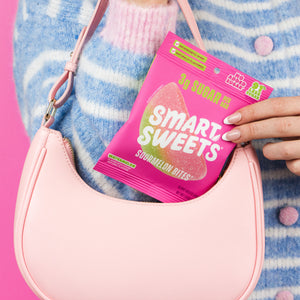 Sourmelon Bites candy bag tucked into a pink shoulder bag. Copy: 3g sugar per bag, 91% less sugar, no synthetic dyes, plant-based candy.