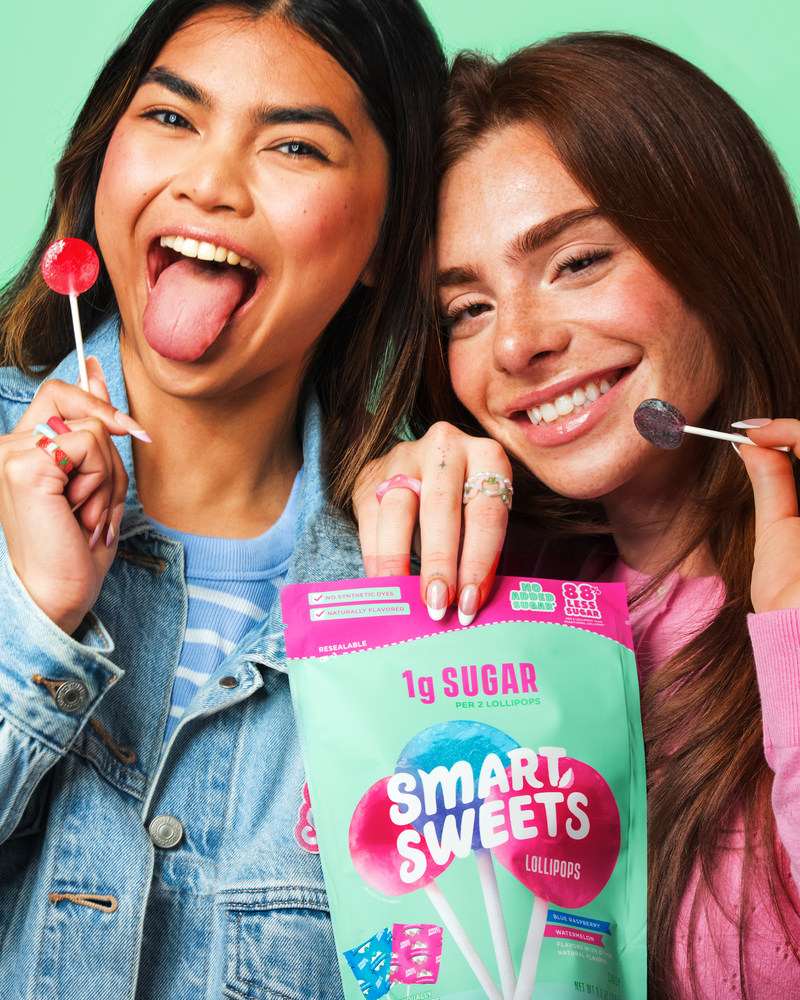 Two smiling people posing with lollipops and a candy bag. Copy on bag: 1g sugar per 2 lollipops, 88% less sugar, blue raspberry & watermelon.