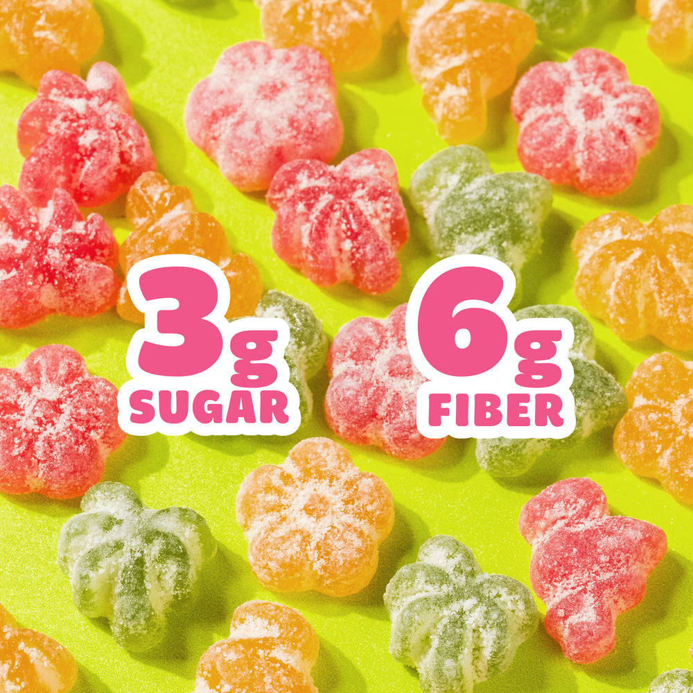 Tropical sour gummy candies scattered on a green background. Large text overlays read "3g SUGAR" and "6g FIBER".