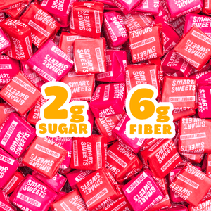Individually wrapped pink and red chewy candies piled together. Large text overlays read "2g SUGAR" and "6g FIBER".